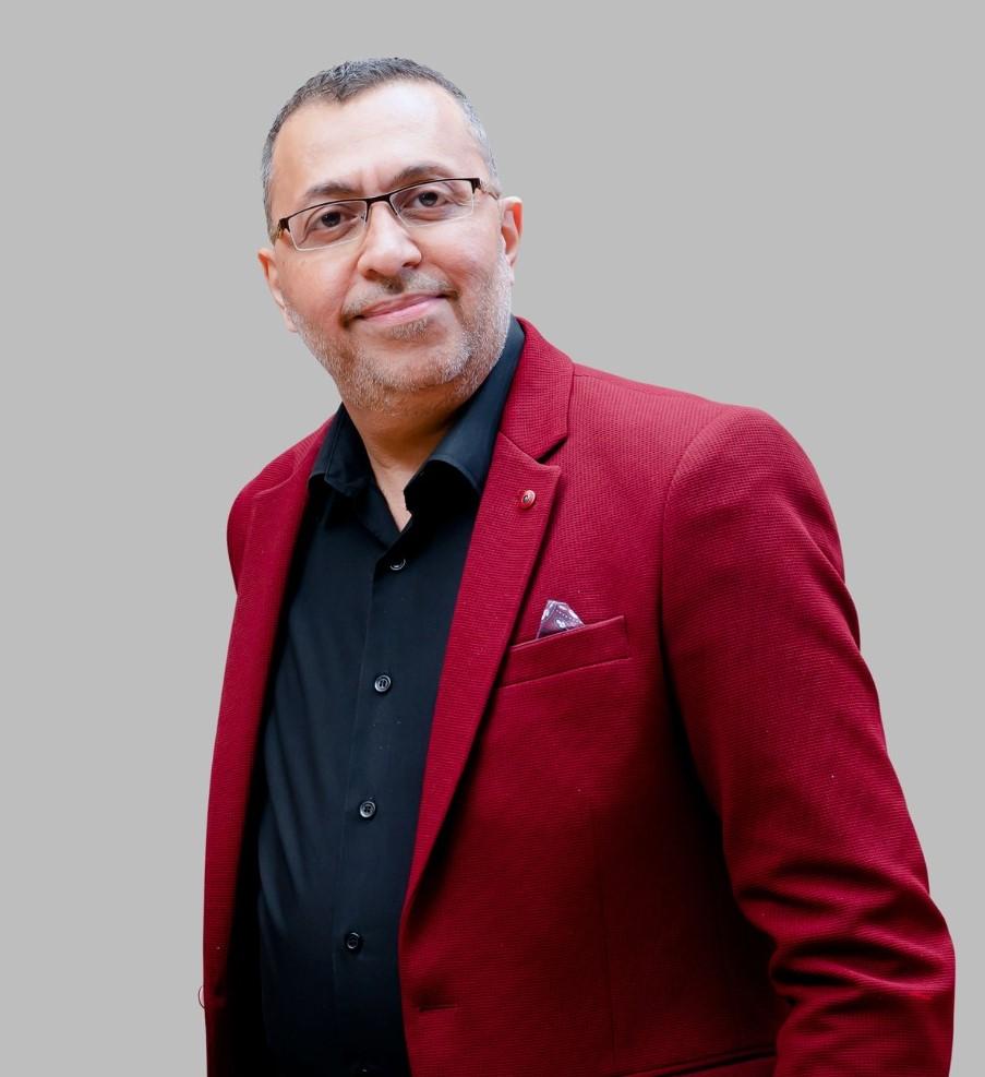 Sanjay Mansukhani, Director and Co-founder of Visioncraft Consultants, in a formal red jacket portrait